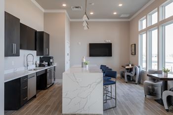 A kitchen with a white marble island and black cabinets.